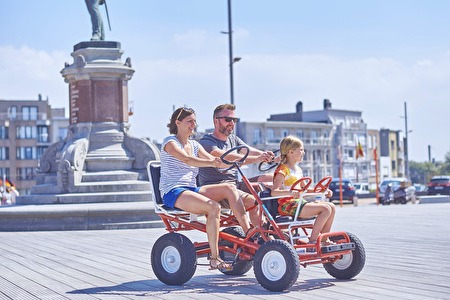 Drei Personen auf einem typischen Go-Kart oder 'Bollerwagen'